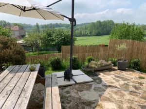 eine Terrasse mit einem Sonnenschirm und einem Holztisch in der Unterkunft Gîte de la Kélidoine in Montigny-sur-Armançon