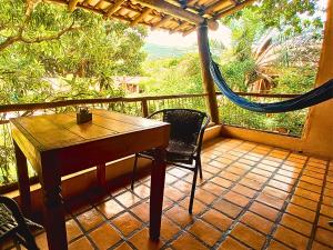 a porch with a table and chairs and a hammock at Recanto Arandu - Boutique Hotel & Retiros in Palmeiras