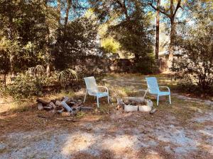 two chairs sitting next to a fire in a yard at A-Frame in the Woods 