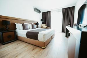 a hotel room with a bed and a television at Palladium Beach Hotel in Dhërmi