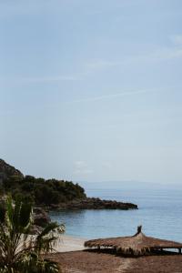 a beach with a straw umbrella and the ocean at Palladium Beach Hotel in Dhërmi