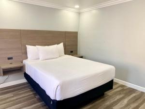 1 dormitorio con 1 cama grande con sábanas blancas en Lone Oak Lodge en Monterrey