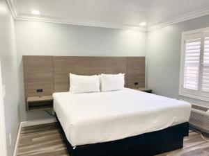 una camera da letto con un grande letto bianco con testiera in legno di Lone Oak Lodge a Monterey