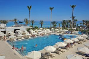 a pool with white umbrellas and people in a resort at Nelia Beach Hotel & Spa in Ayia Napa