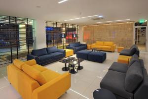 a living room with couches and yellow and blue chairs at Nelia Beach Hotel & Spa in Ayia Napa