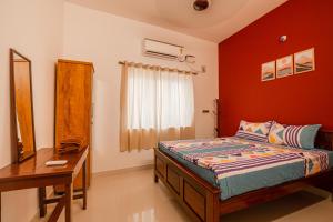 1 dormitorio con cama, escritorio y espejo en Maison Annai en Pondicherry