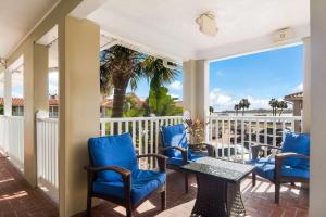 a porch with blue chairs and a table and a palm tree at Best Western Historic Bayfront in Saint Augustine
