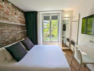 パリにあるベストウエスタン ホテル ル モンパルナスの白いベッドとレンガの壁が備わるベッドルーム1室が備わります。