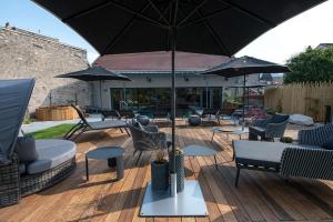 une terrasse avec des chaises, des tables et un parasol dans l'établissement Best Western Premier Le Chapitre Hotel and Spa, à Remiremont