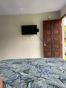 een slaapkamer met een bed en een televisie aan de muur bij Casa de campo aconchegante in Córrego do Bom Jesus
