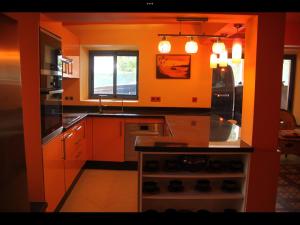 een keuken met oranje muren en een fornuis met oven bij Dar Nfis piscine hydro massage Privée, jet ski, Agafay in Lalla Takerkoust