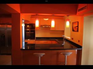 een keuken met oranje muren en een zwart aanrecht bij Dar Nfis piscine hydro massage Privée, jet ski, Agafay in Lalla Takerkoust
