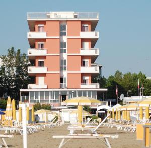 un grande edificio rosa con sedie e ombrelloni sulla spiaggia di Hotel Nelson a Rimini