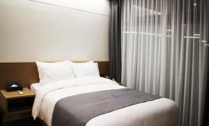 ein Schlafzimmer mit einem großen Bett und einem Fenster in der Unterkunft Hotel Parangvue in Goseong