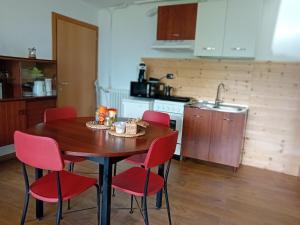 cocina con mesa de madera y sillas rojas en Serok: Casa nel Bosco con Bio Sauna en Civo