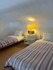 Dos camas en una habitación con una lámpara sobre una mesa. en Monte da Bela Vista, Colos, en Colos