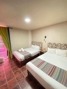a hotel room with two beds and a window at Hotel Flamingos in Guadalajara