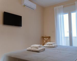 sypialnia z 2 ręcznikami na łóżku z telewizorem z płaskim ekranem w obiekcie Venetiko rooms w Chios