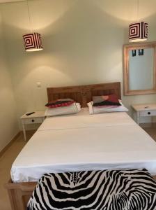 Ossoma House في لواندا: غرفة نوم بسرير كبير عليها بطانية حمار وحشري