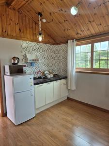 uma cozinha com electrodomésticos brancos e um tecto de madeira em Ganghwa Sweet House Pension em Incheon
