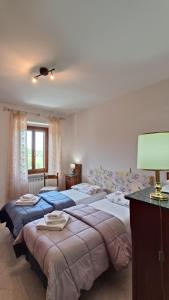 a bedroom with three beds and a table with a lamp at Il Fiordaliso in Preci