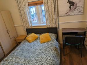 um quarto com uma cama com almofadas amarelas e uma janela em London Central Large Acton House em Londres
