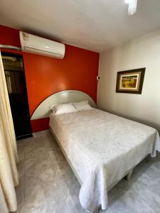 um quarto com uma cama e uma parede vermelha em Carolina's Hostel em Piura