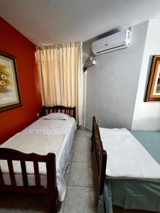 duas camas num quarto com paredes vermelhas em Carolina's Hostel em Piura