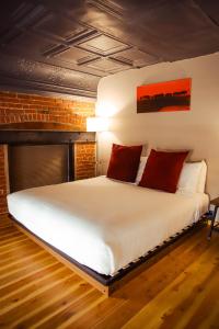 um quarto com uma grande cama branca com almofadas vermelhas em The Hotel Sturgis em Sturgis