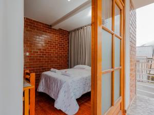 - une chambre avec un lit et un mur en briques dans l'établissement Las Yungas Hospedaje, à Oxapampa