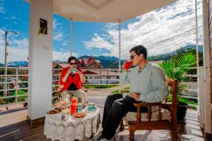 2 personnes assises sur une terrasse couverte avec une table dans l'établissement Las Yungas Hospedaje, à Oxapampa