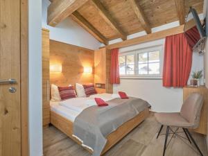 a bedroom with a bed and a chair and a window at Bergbiberhaus L in Piesendorf