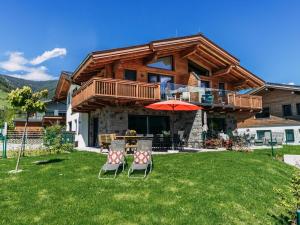 ein Haus mit zwei Stühlen und einem Sonnenschirm im Hof in der Unterkunft Tauern Lodge L in Piesendorf