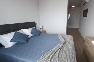 een slaapkamer met een bed met blauwe en witte kussens bij Sol do Til Apartment in Funchal