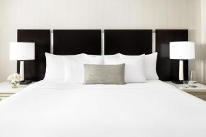 ein großes weißes Bett mit weißen Kissen und zwei Lampen in der Unterkunft The Gregorian New York City in New York