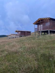 ein paar Gebäude auf einem Hügel auf einem Feld in der Unterkunft Chalé Campos Da Serra in São José dos Ausentes
