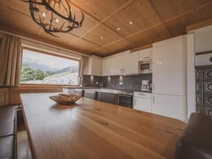kuchnia z drewnianym stołem i dużym oknem w obiekcie Bella Vista XL w mieście Wald im Pinzgau