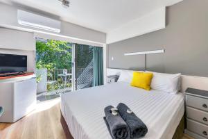 1 dormitorio con 1 cama, TV y balcón en Paravista Motel, en Darwin