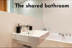 ein weißes Badezimmer mit einem Waschbecken und einem Spiegel in der Unterkunft Double Room with Private Balcony in London