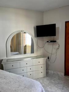 um quarto com uma cómoda e uma televisão na parede em Carolina's Hostel em Piura