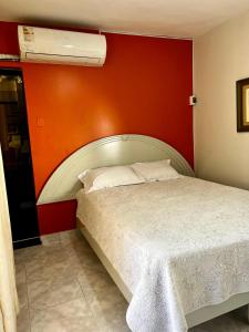 um quarto com uma cama branca e uma parede vermelha em Carolina's Hostel em Piura