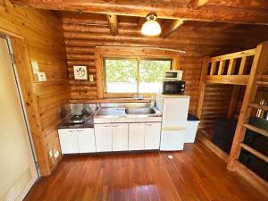 a kitchen in a log cabin with a sink and a microwave at Tokashiki Guest House in Tokashiki