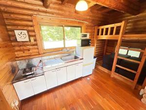 eine Küche in einem Blockhaus mit einer Spüle und einer Mikrowelle in der Unterkunft Tokashiki Guest House in Tokashiki