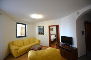 a living room with a yellow couch and a television at Serenity at Sveti Stefan in Sveti Stefan