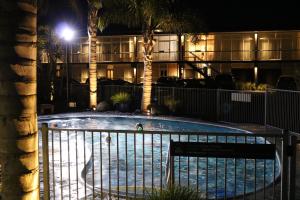a swimming pool in front of a hotel at night at Aura Accommodation in Rotorua