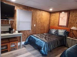 een slaapkamer met een bed, een bureau en een televisie bij Falls Motel in Niagara Falls