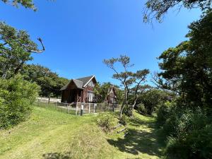 an old house in a field with a fence at Tokashiki Guest House in Tokashiki