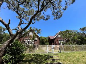 an old house with a fence and a tree at Tokashiki Guest House in Tokashiki