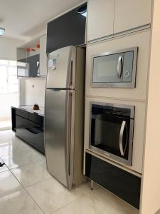 a kitchen with a stainless steel refrigerator and microwave at Beautiful condo by the shore in Santos