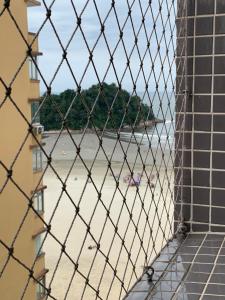 a view of the beach through a wire fence at Beautiful condo by the shore in Santos